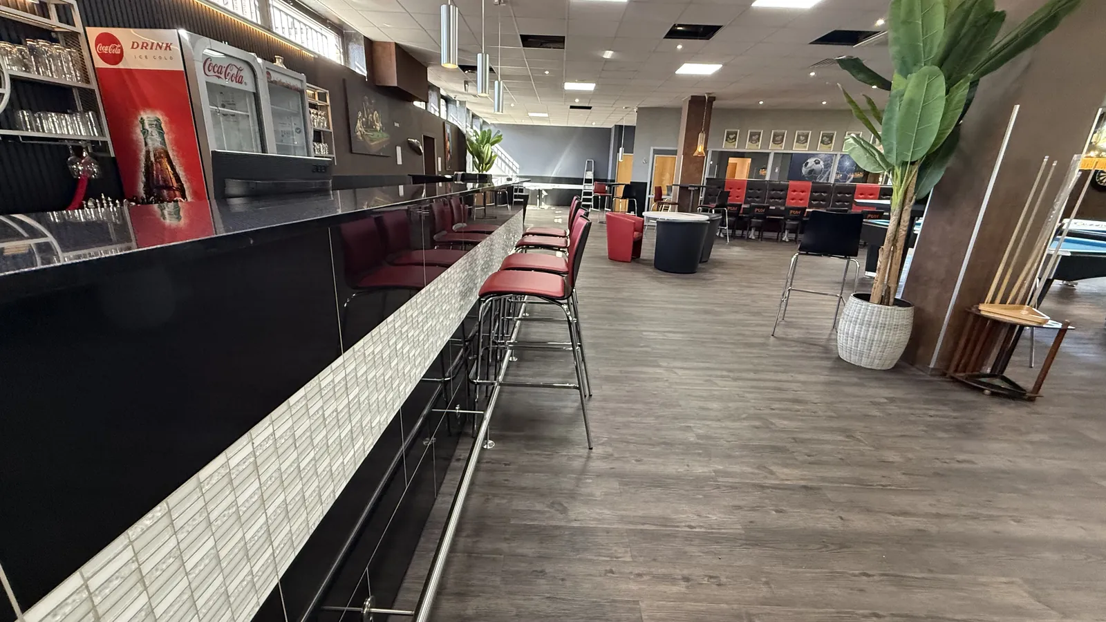 Bar der Players Lounge Voerde mit langer Theke, roten Hockern und Regal dahinter